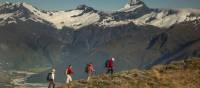 Trekkers on Buchanan peak with Mount Aspiring behind, walking above Matukituki valley, near Lake Wanaka | Colin Monteath